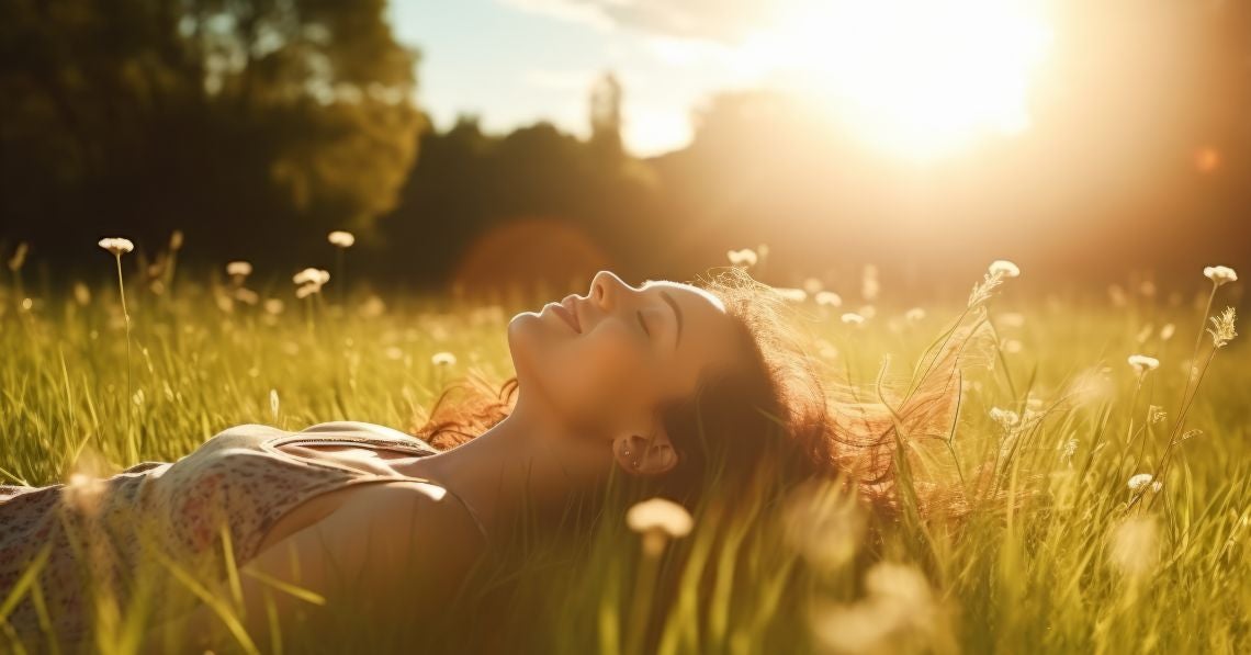 Woman laying in a field with flowers and sunshine all around