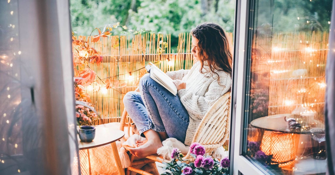 woman reading on her balcony at dusk