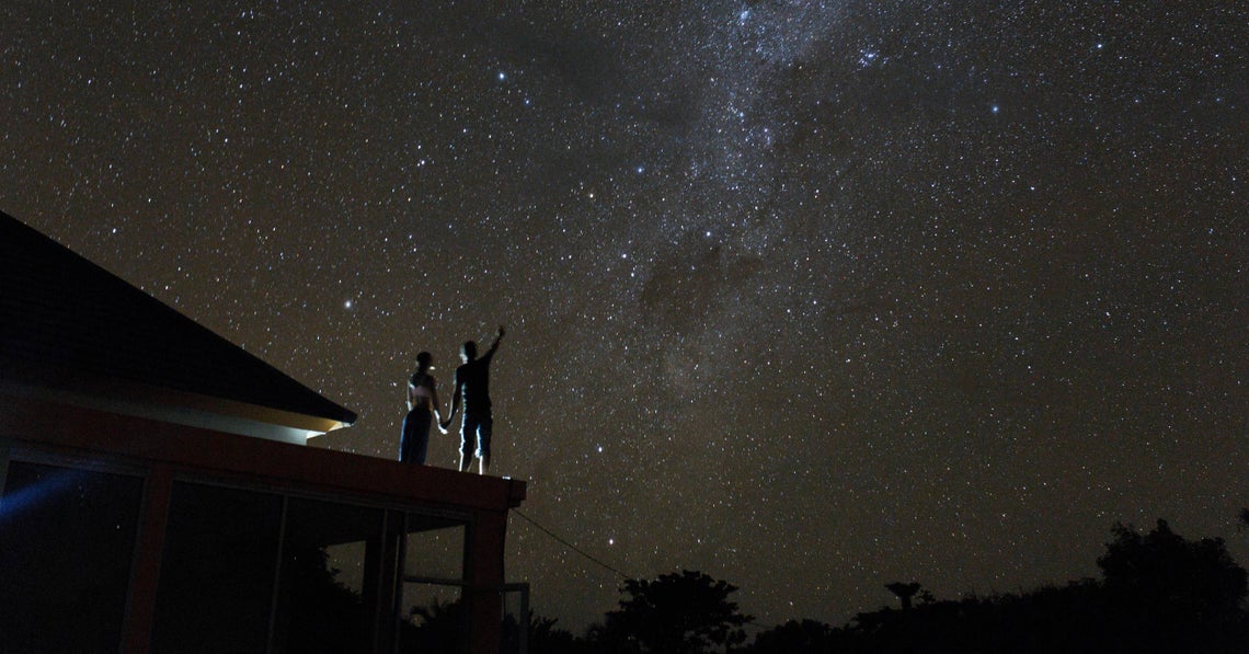 a couple star gazing from the roof of their house