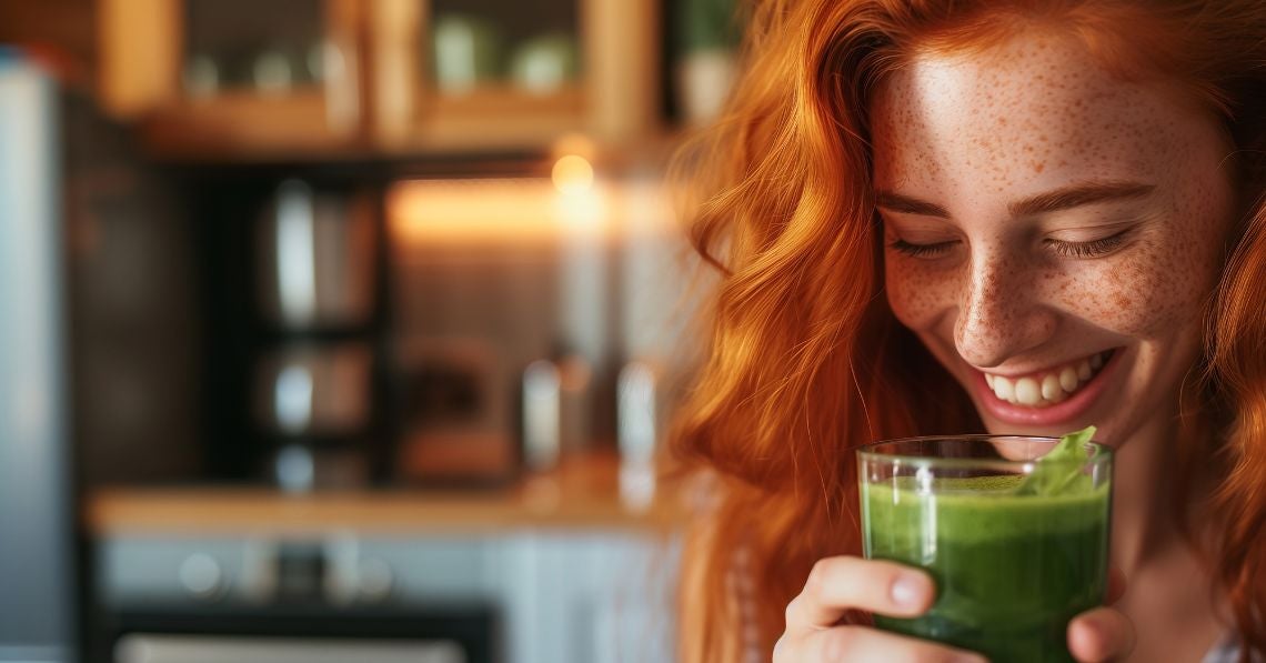 Beautiful, happy woman drinking a green smoothie