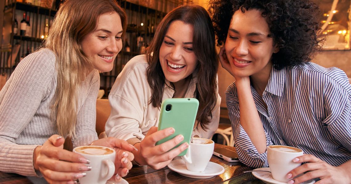 Women at a coffee shop looking at phone