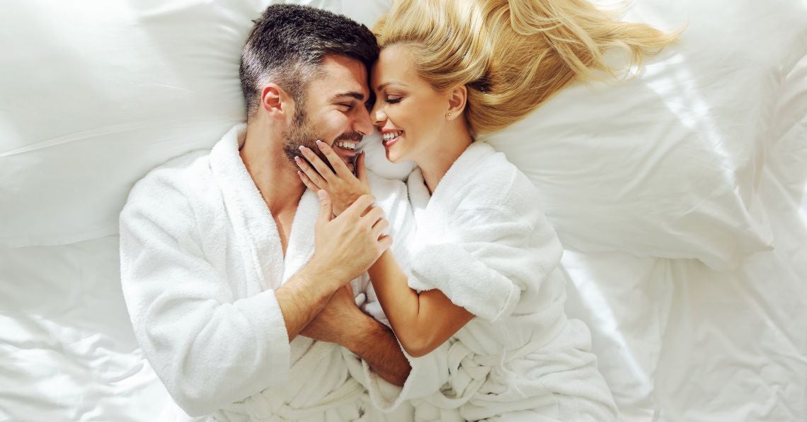 Man and woman in bed about to kiss