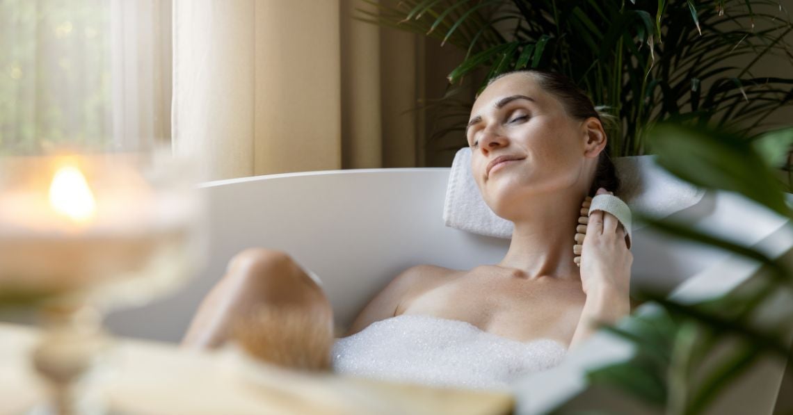 Woman taking a bath massaging her neck with massage tool