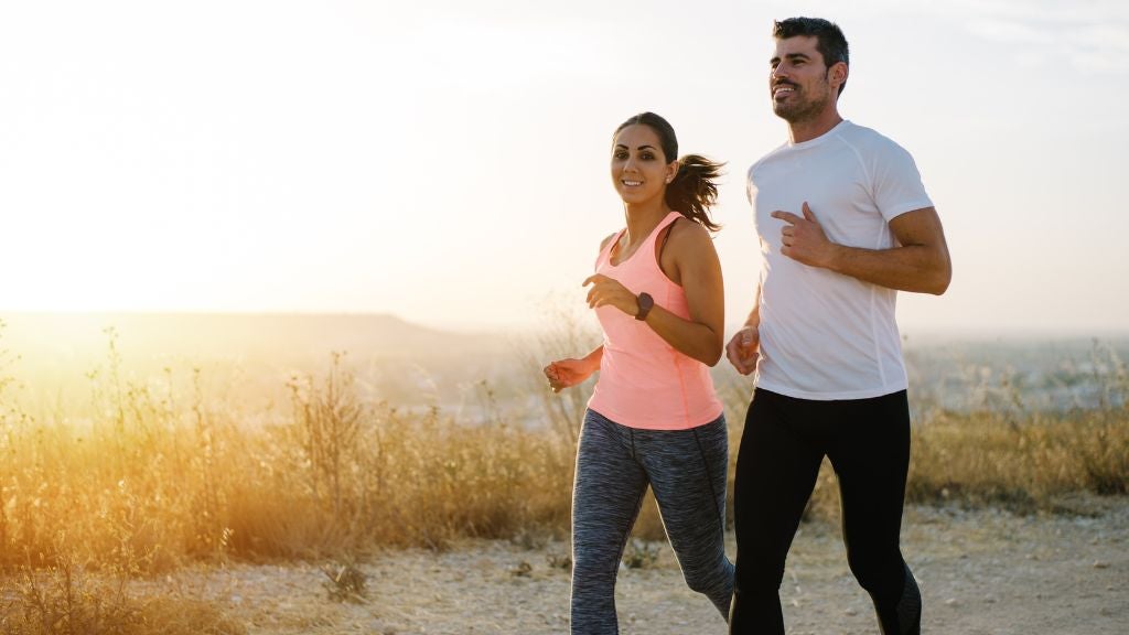 Athletic man and woman jogging with the sunset in the background