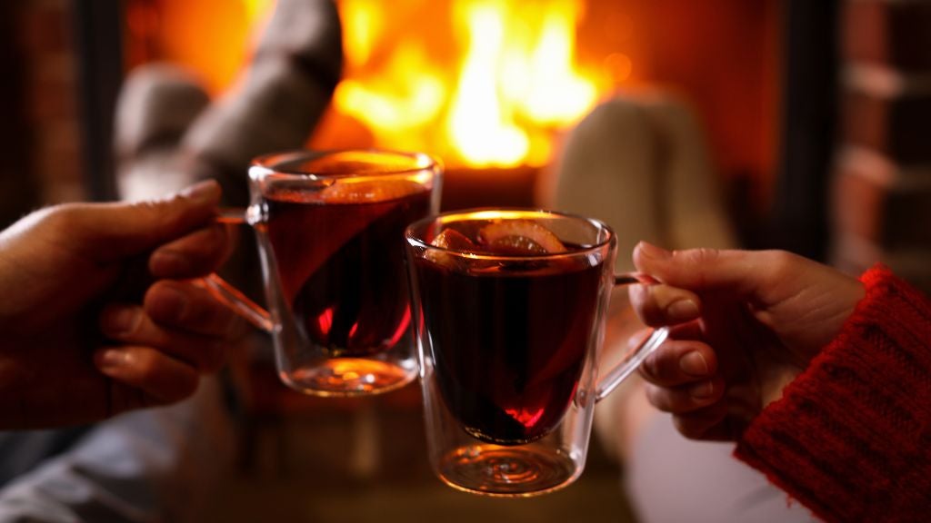 Two people enjoying a hot toddy by the fireplace