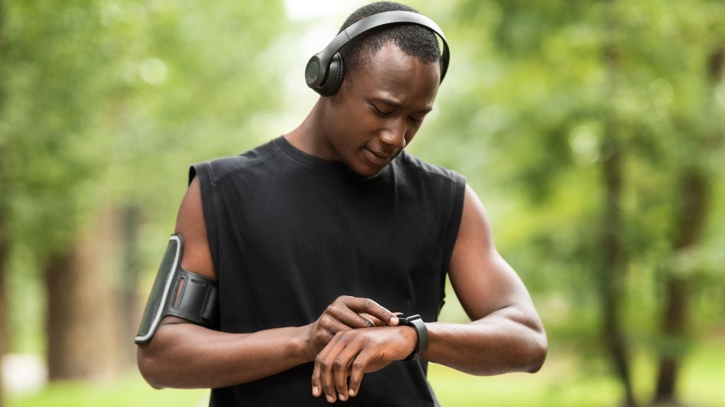 Man with headphones, smartwatch, and a phone arm band about to go jogging