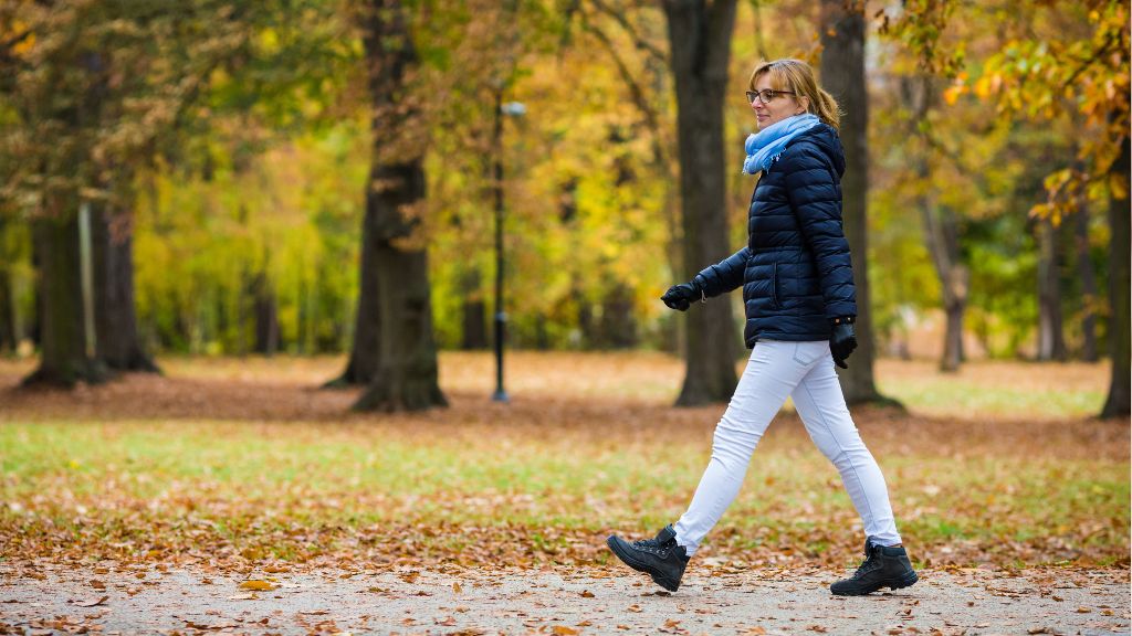 Woman in warm clothes taking a leisurely stroll in a park like setting.