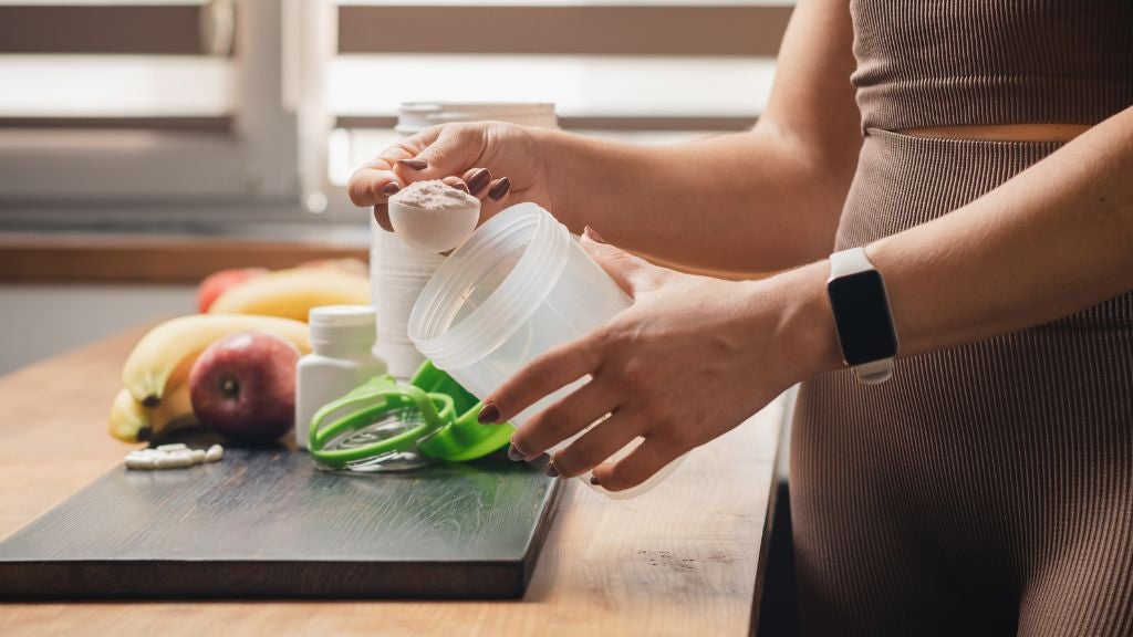 Woman in kitchen making a healthy smoothie with creatine