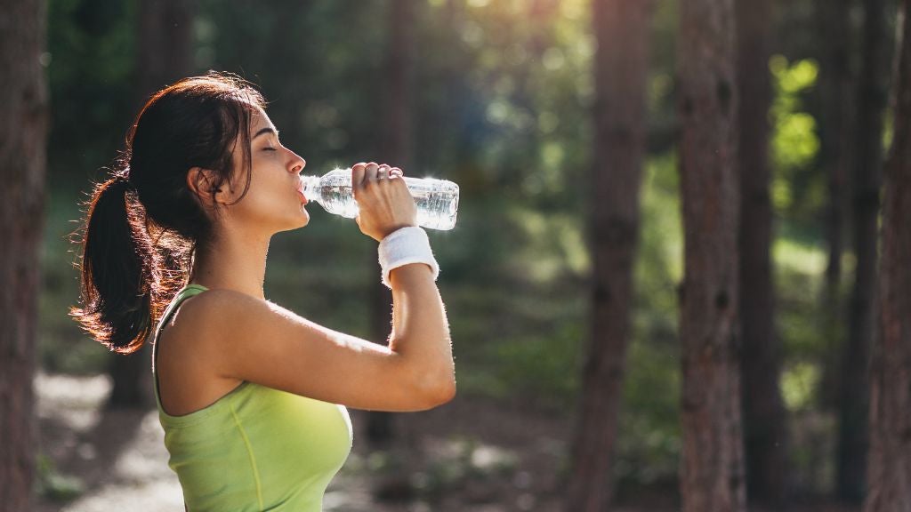 Woman stopping her workout to drink a bottle of water