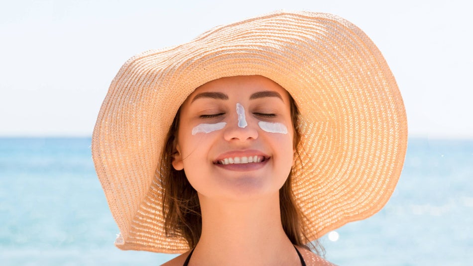 a woman wearing sunscreen and a sun hat at the beach